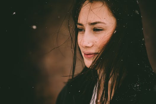 一位深色头发的年轻女子，凝视着飘落的雪，神情沉思，唤起了冬日的孤寂