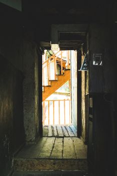 Moody interior featuring a rustic corridor and wooden staircase in a historic Tbilisi building.