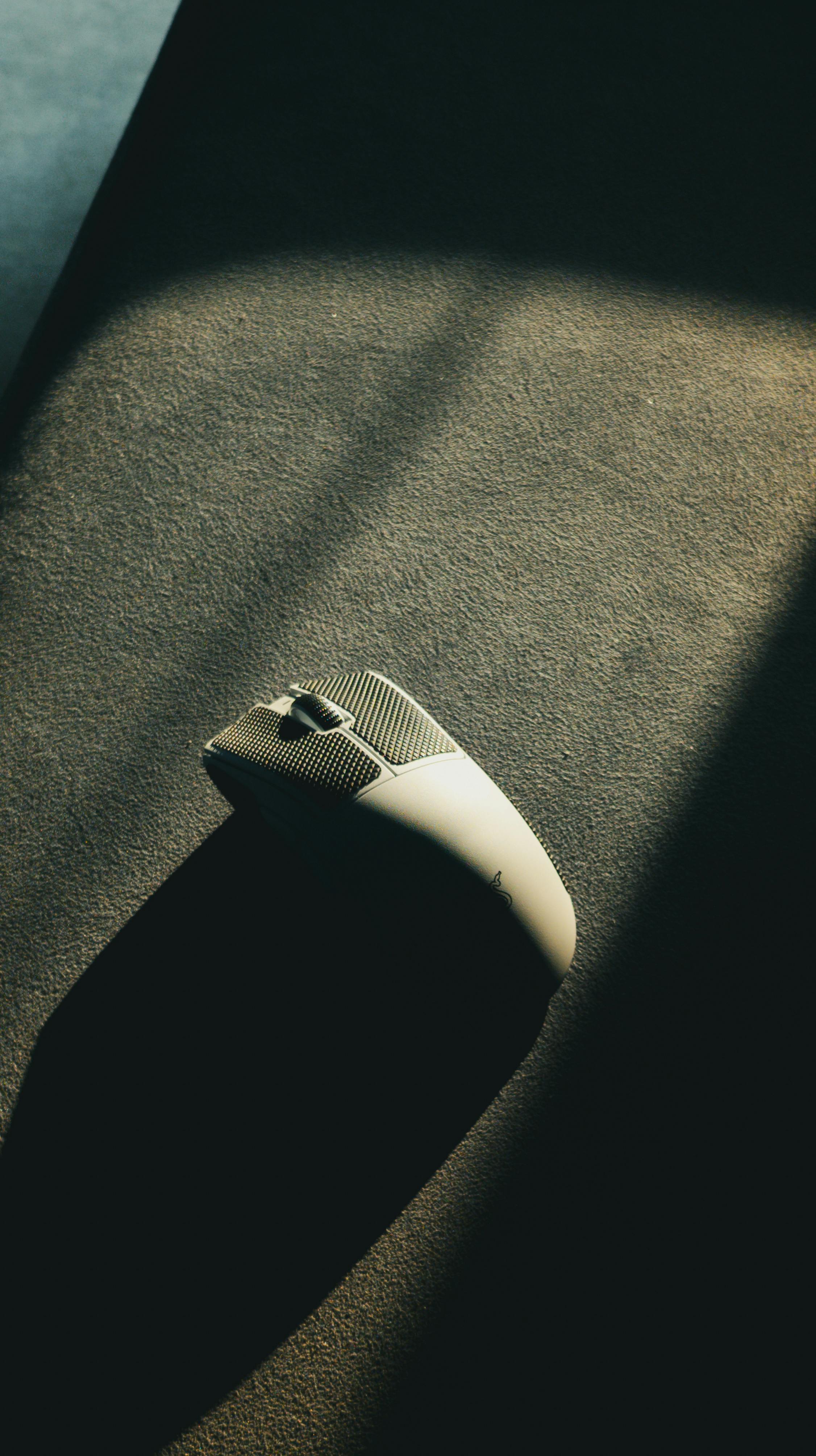 Kostenlos Eine elegante, beleuchtete Computermaus auf einer strukturierten Oberfläche mit dramatischem Licht- und Schattenspiel. Stock-Foto