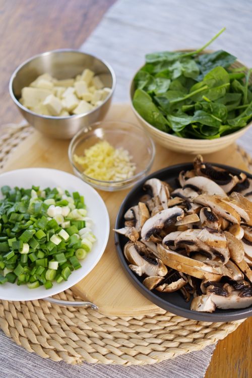 Free A selection of fresh ingredients including mushrooms, tofu, spinach, and scallions ready for cooking. Stock Photo