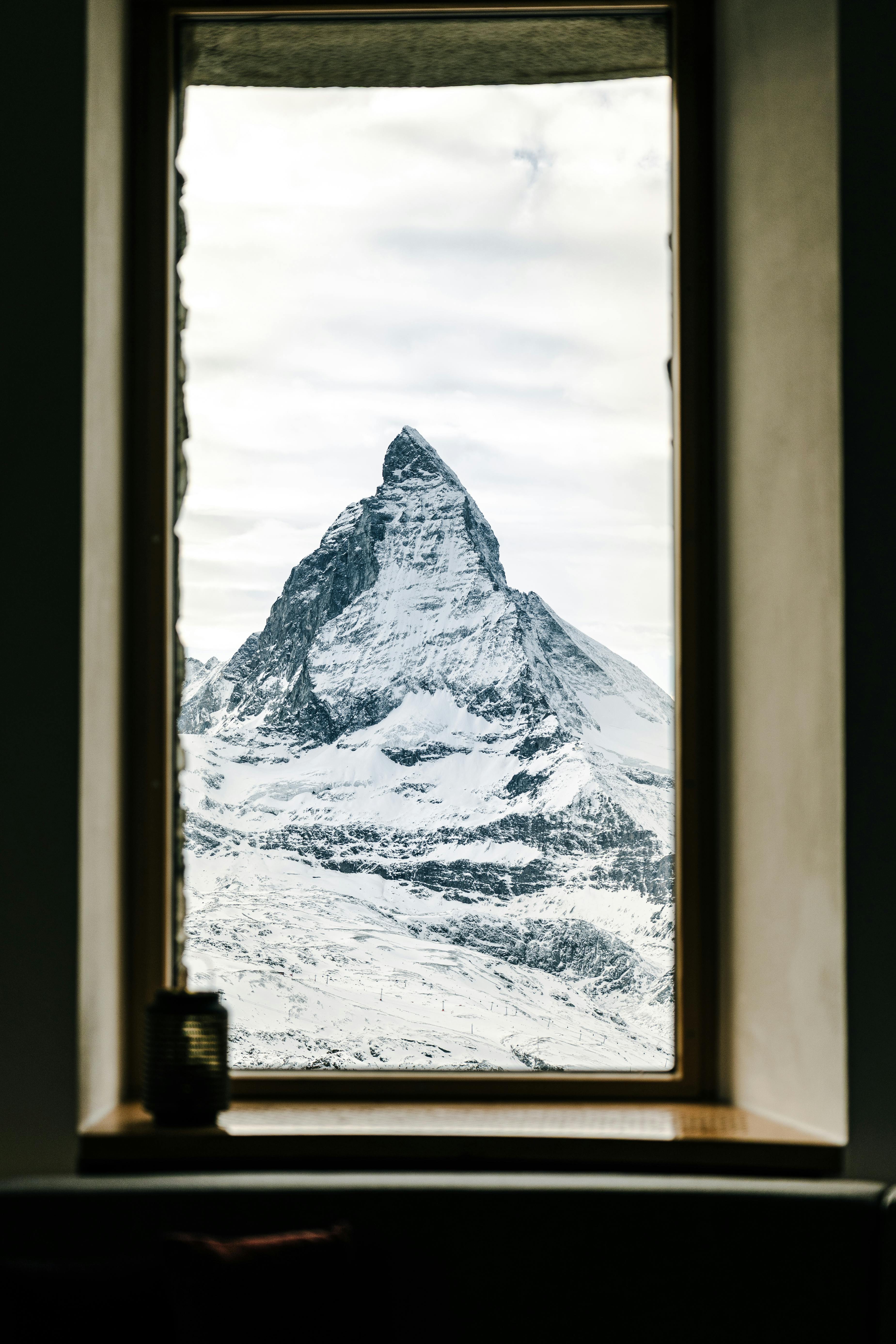 Framed view of the snow-covered Matterhorn mountain peak through a window.
