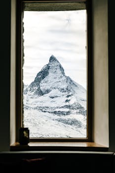 Framed view of the snow-covered Matterhorn mountain peak through a window.