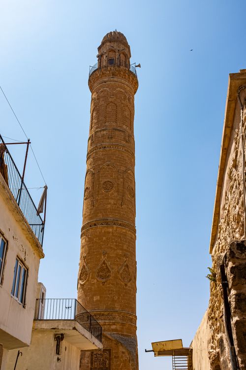 Free A historical brick minaret tower rises against a clear blue sky, showcasing intricate architecture. Stock Photo