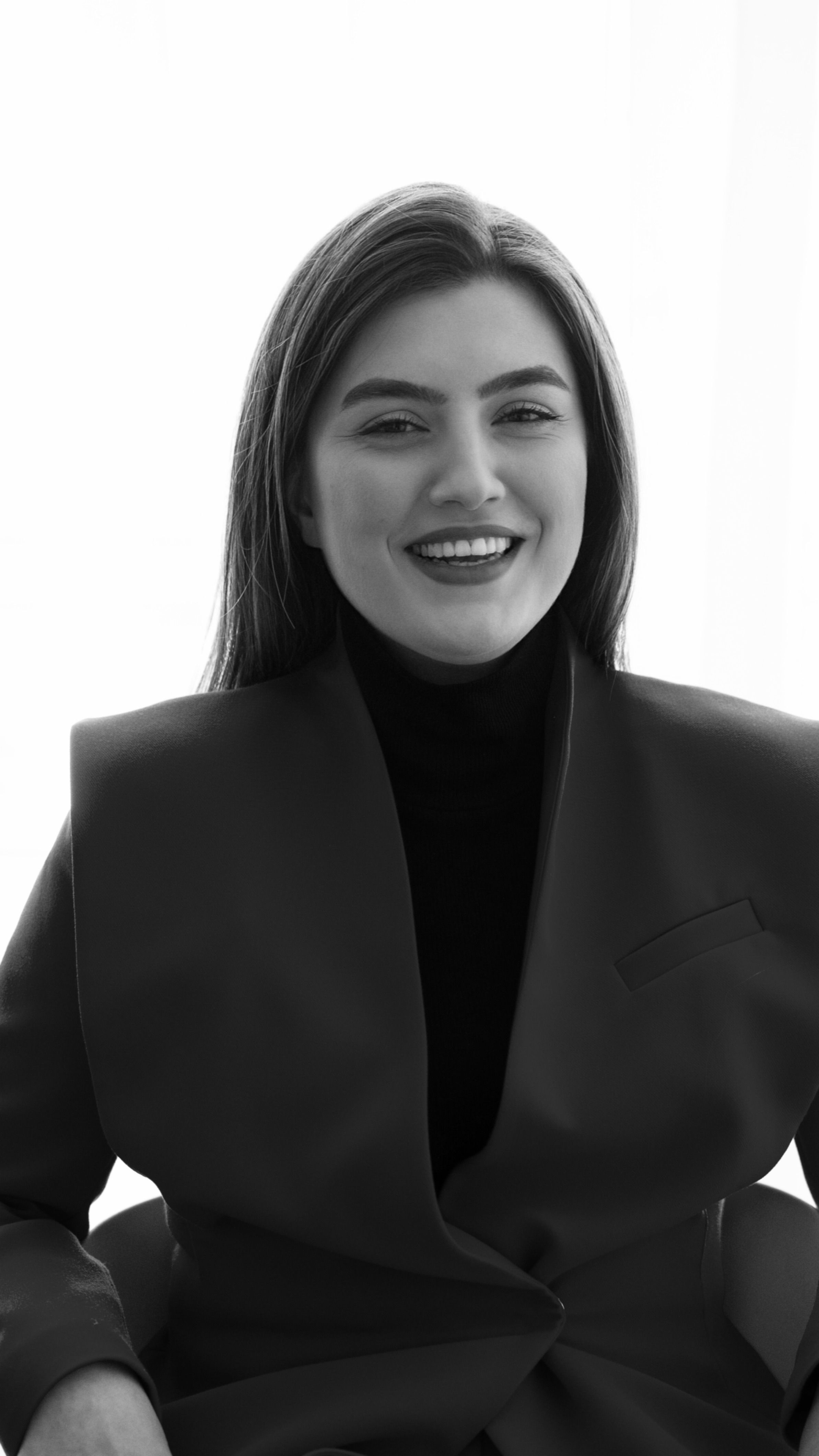Elegant black and white portrait of adult woman in stylish jacket, smiling warmly.
