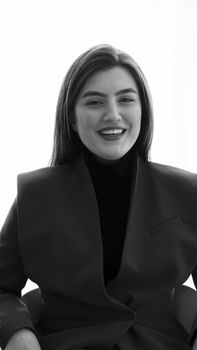 Elegant black and white portrait of adult woman in stylish jacket, smiling warmly.