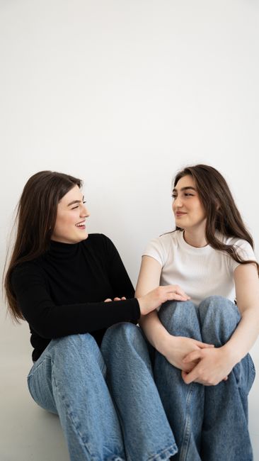 Two young women sitting on the floor, sharing a moment of friendship and joy.