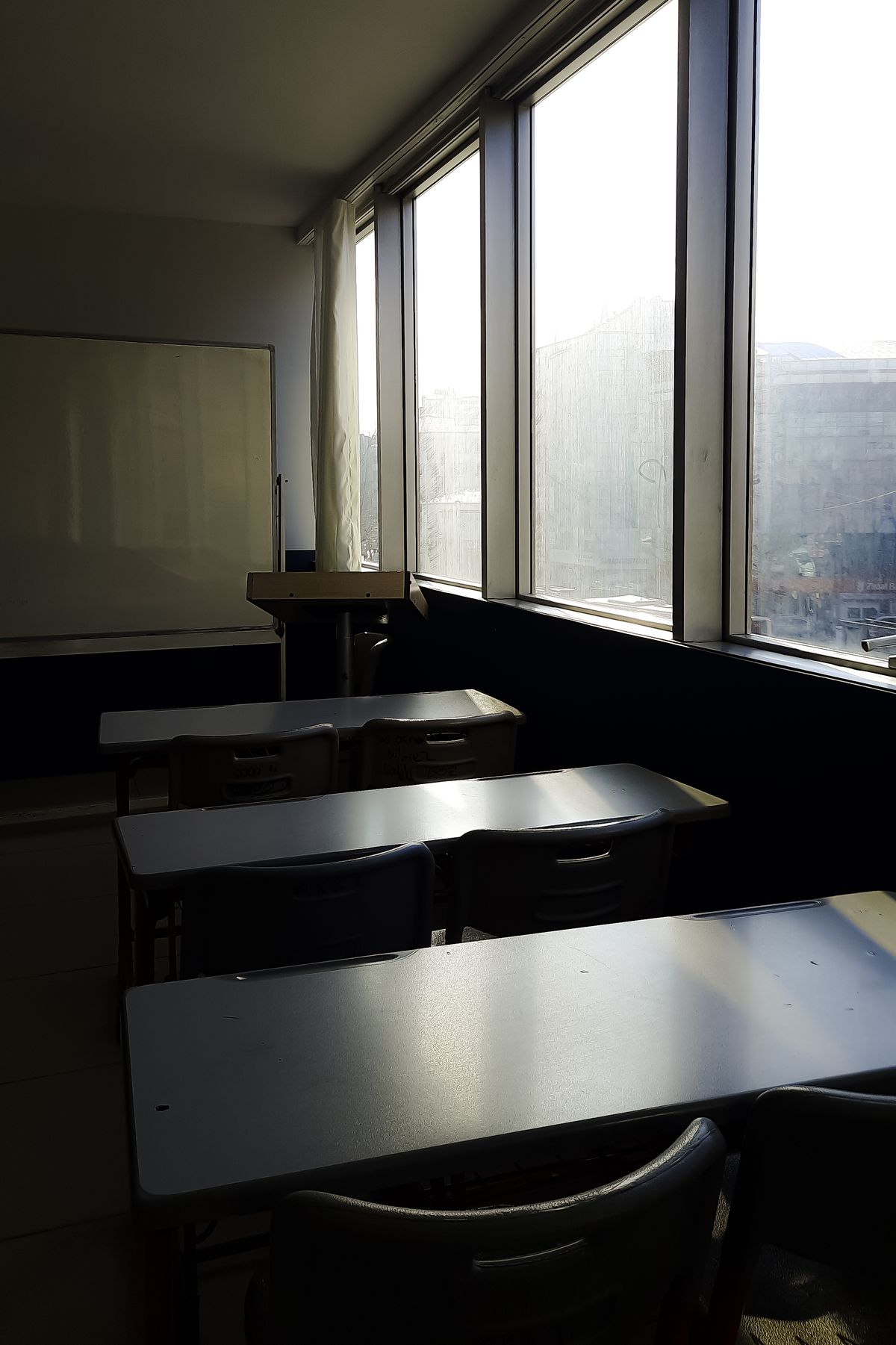 Sonnendurchflutetes Klassenzimmer mit leeren Pultreihen und großen Fenstern