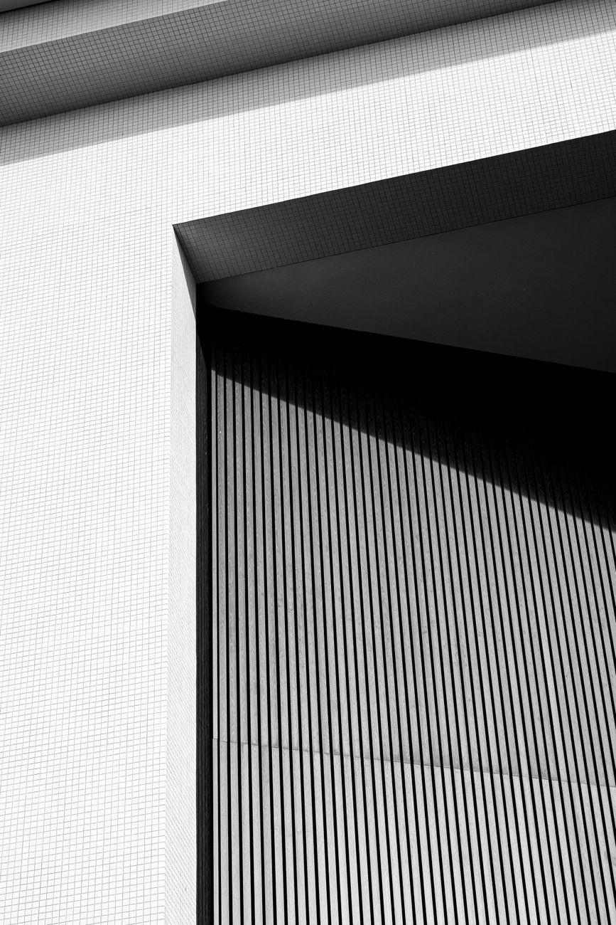 Black and white abstract of an angular building facade with contrasting shadows.