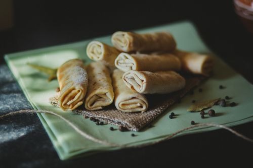 Free Delicious homemade crepes filled with spices, served on woven fabric, perfect for savory snacking. Stock Photo