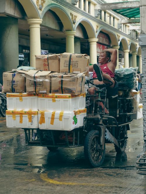Free A vendor relaxes on a heavily loaded tricycle in a busy street market in NCR, Philippines. Stock Photo