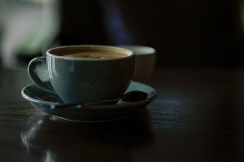 Free A warm coffee cup on a wooden table creates a cozy, dark ambiance. Stock Photo