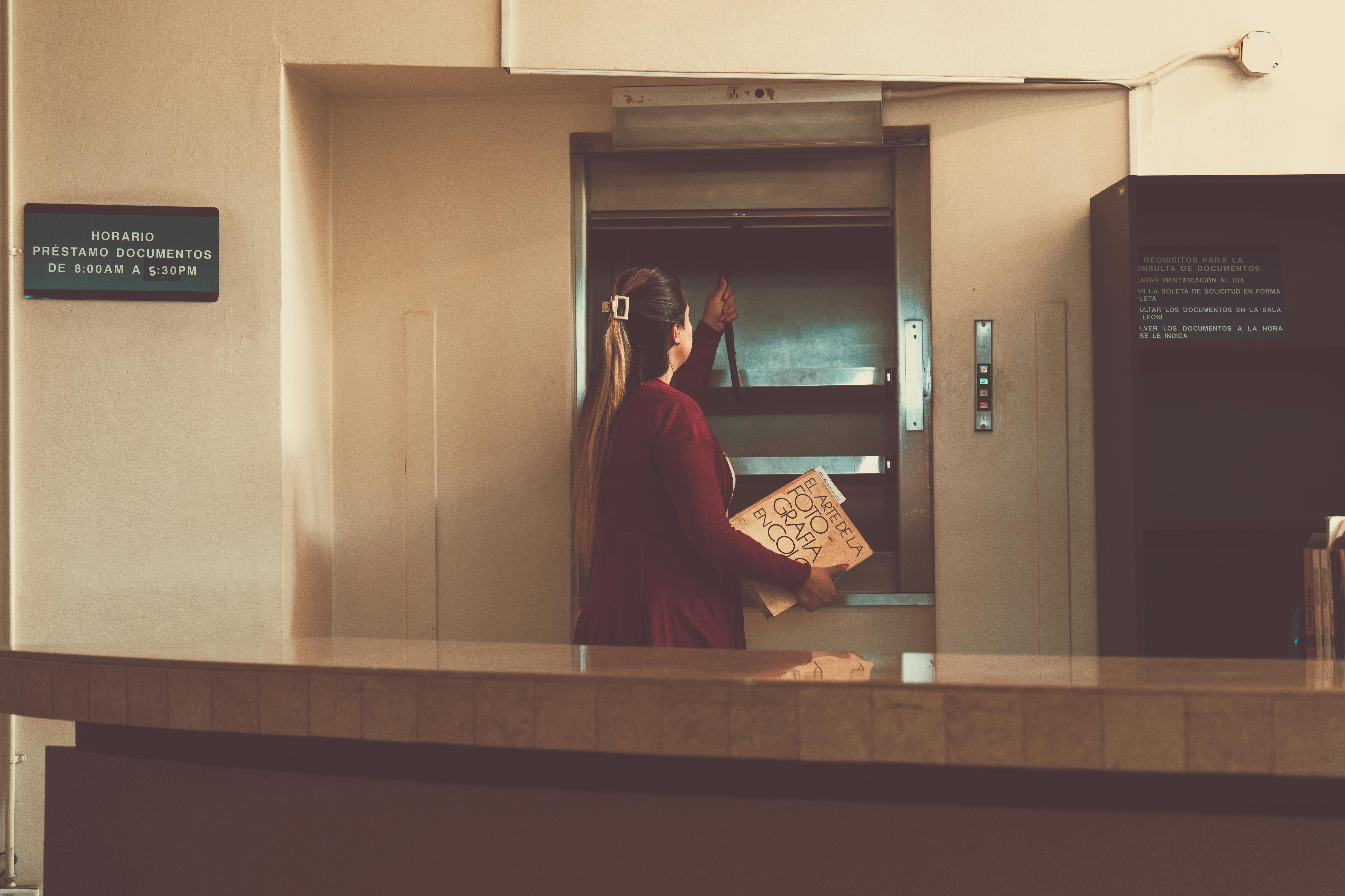 Miễn phí Một phụ nữ đang sử dụng thang máy vận chuyển thức ăn trong thư viện ở San José, Costa Rica. Ảnh lưu trữ