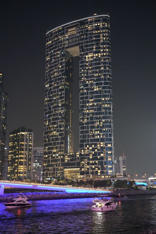 Free Stunning view of the illuminated Dubai Marina Tower at night with boats on the water. Stock Photo