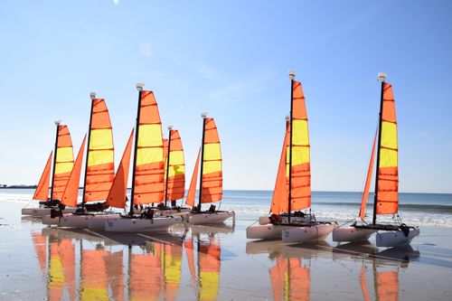 Free Colorful catamarans on a sunny beach reflecting on the wet sand. Stock Photo