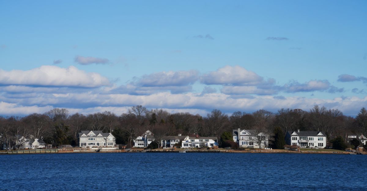 Charming waterfront houses with calm water and a clear sky, ideal for serene living.
