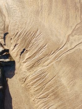 Rippling sand patterns on a sunny beach in Casablanca, Morocco.
