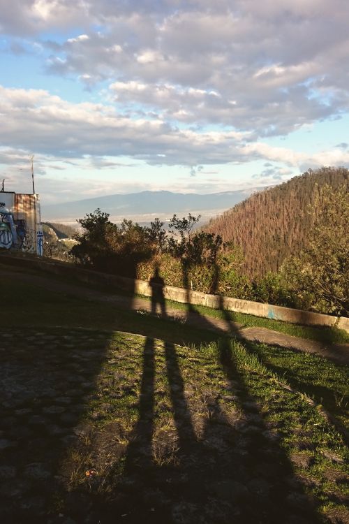 Free A serene mountain landscape with human shadows and graffiti under a vibrant sky. Stock Photo