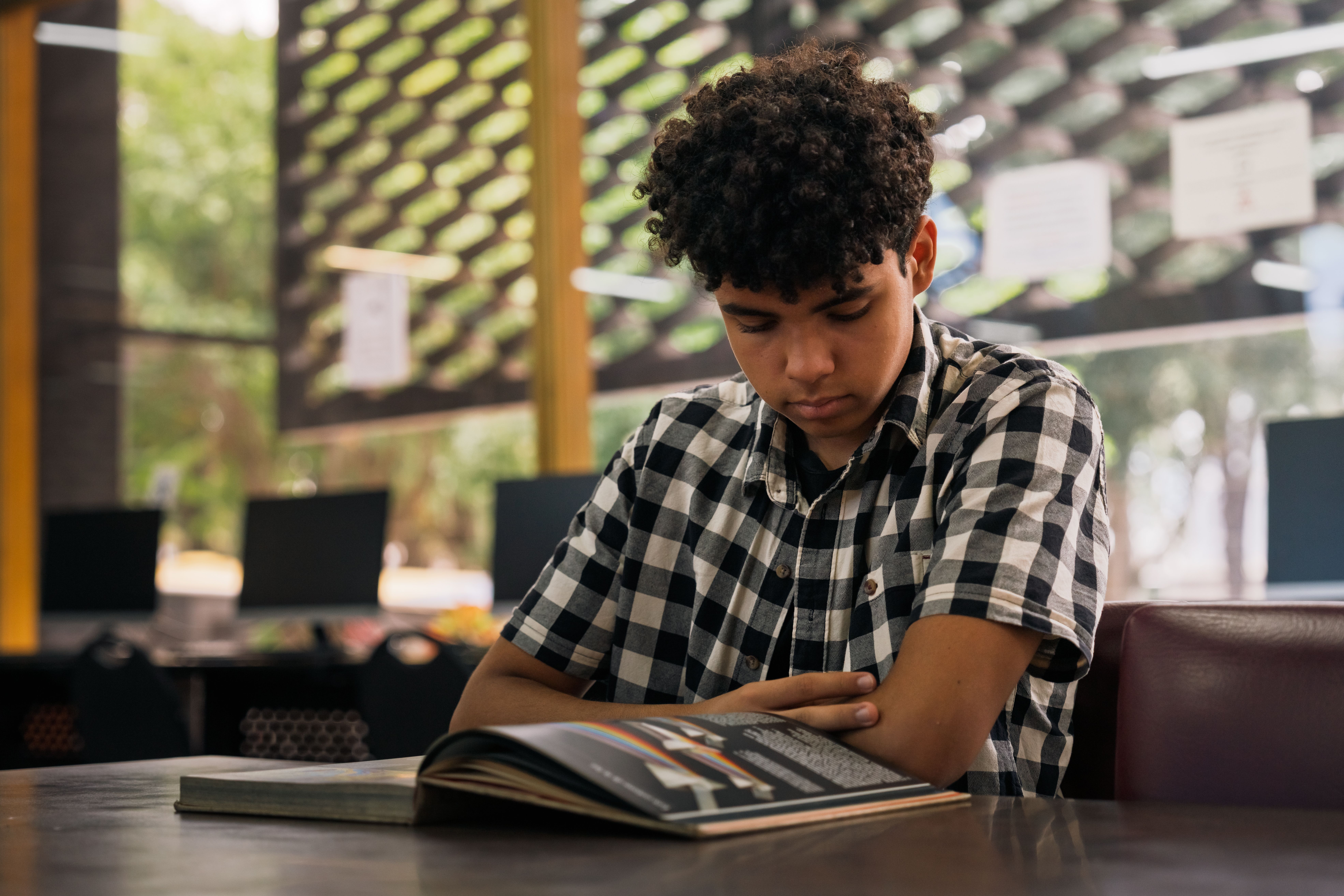 Teenager reading a book in an indoor library setting in San José, Costa Rica. | BocaVibe