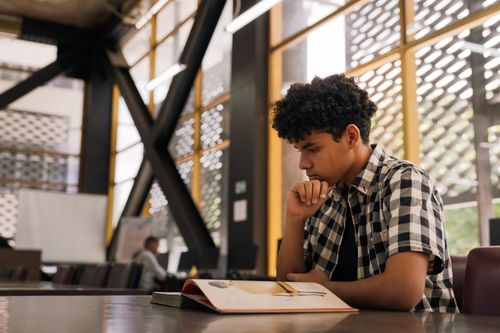 Free Young man studying in a contemporary library setting in San José, Costa Rica. Stock Photo