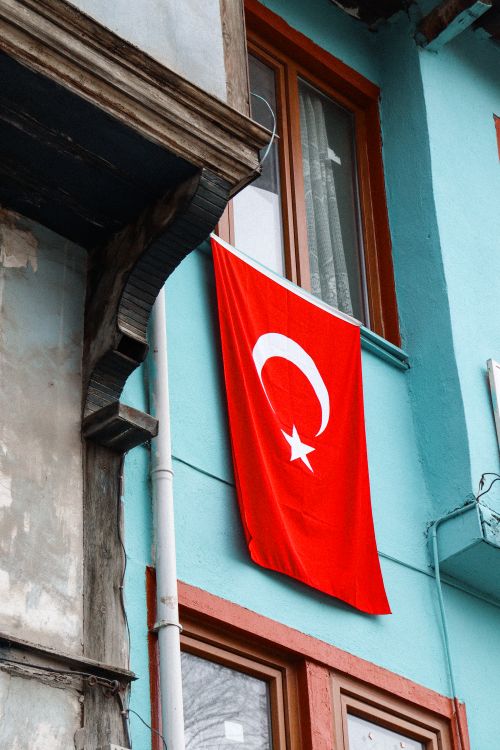 Free Turkish flag displayed on a blue building facade, showcasing national pride. Stock Photo