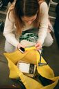一名妇女在室内一边拿着智能手机，一边仔细检查购物袋里的物品