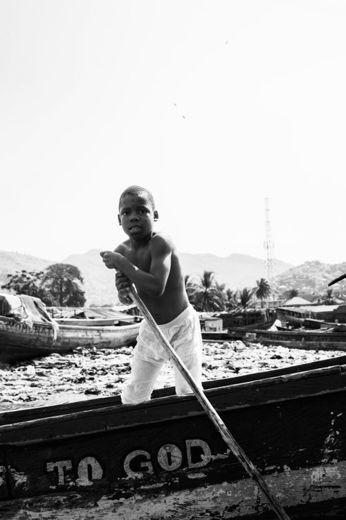 Free Black and white photo of a young boy steering a boat in Monrovia, capturing local life. Stock Photo