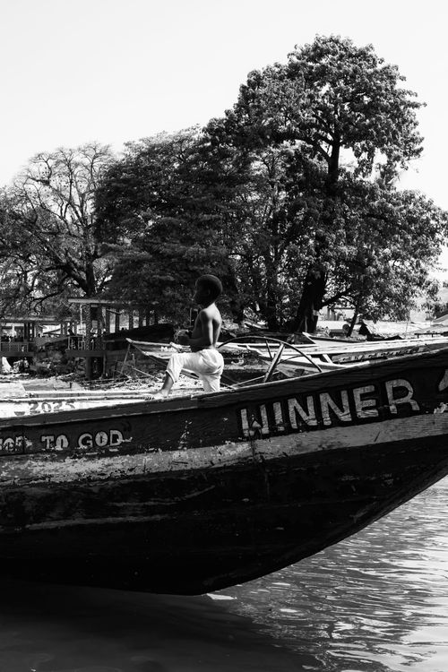 Free A black and white image of a child on a wooden boat named 'WINNER'. Stock Photo
