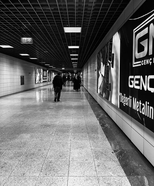 Free Monochrome view of a subway tunnel with people walking, creating a dramatic urban scene. Stock Photo