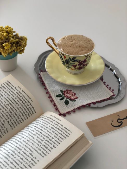 A warm coffee paired with a book and floral elements on a stylish tray, perfect for a relaxing read.