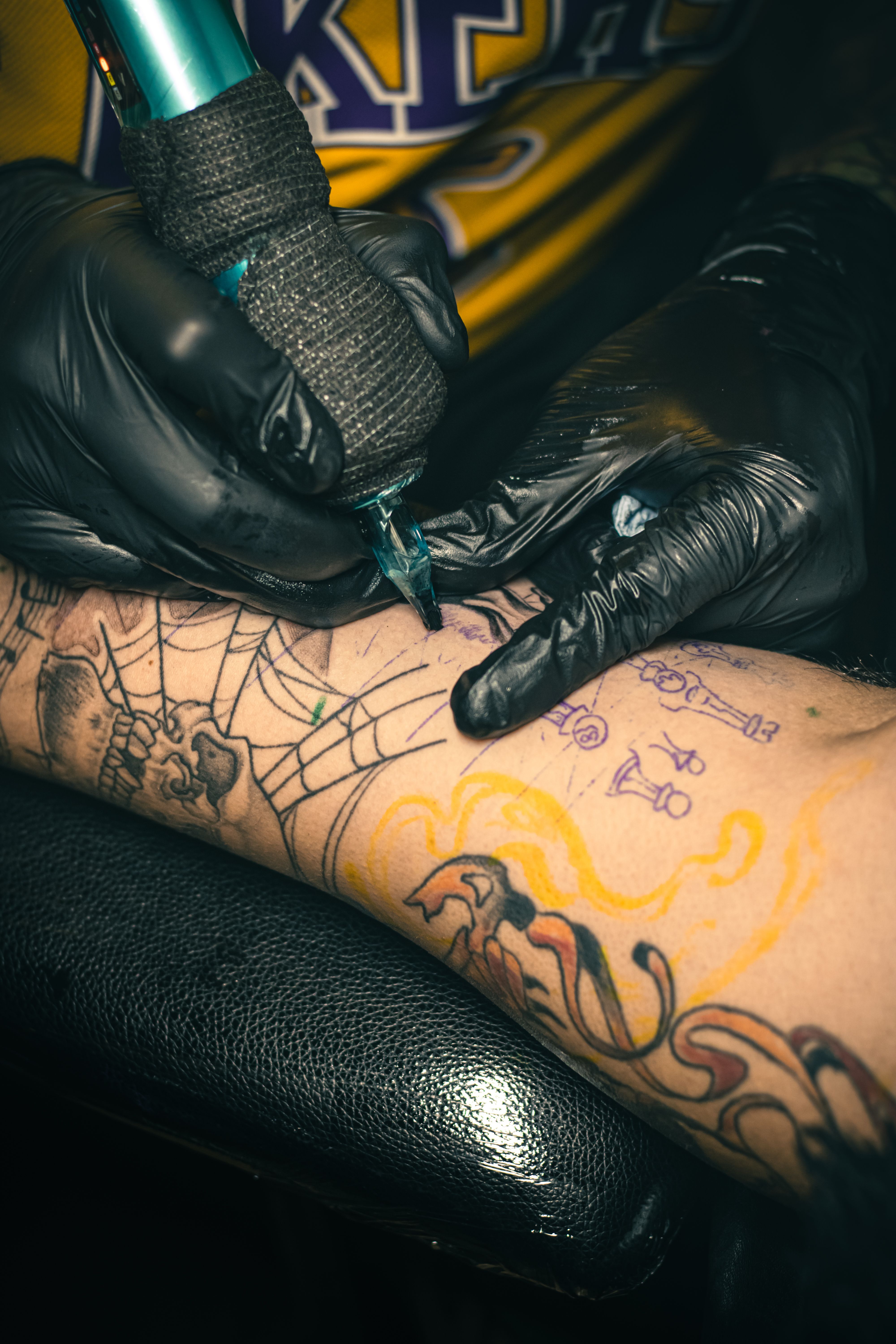 Tattoo artist creating intricate designs on an arm with precise craftsmanship.