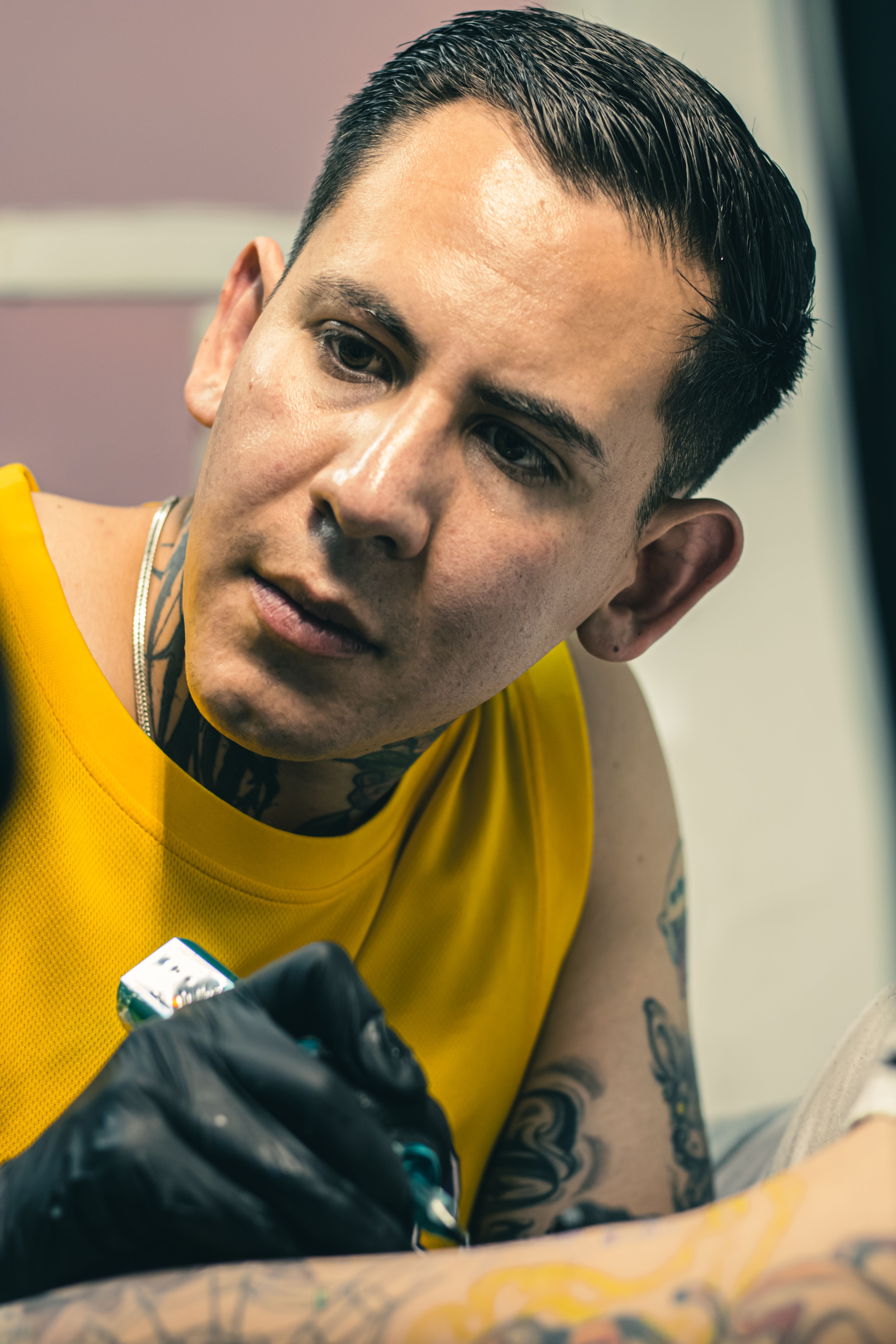 Tattoo artist intently working on a client's arm with intricate designs in a tattoo studio.