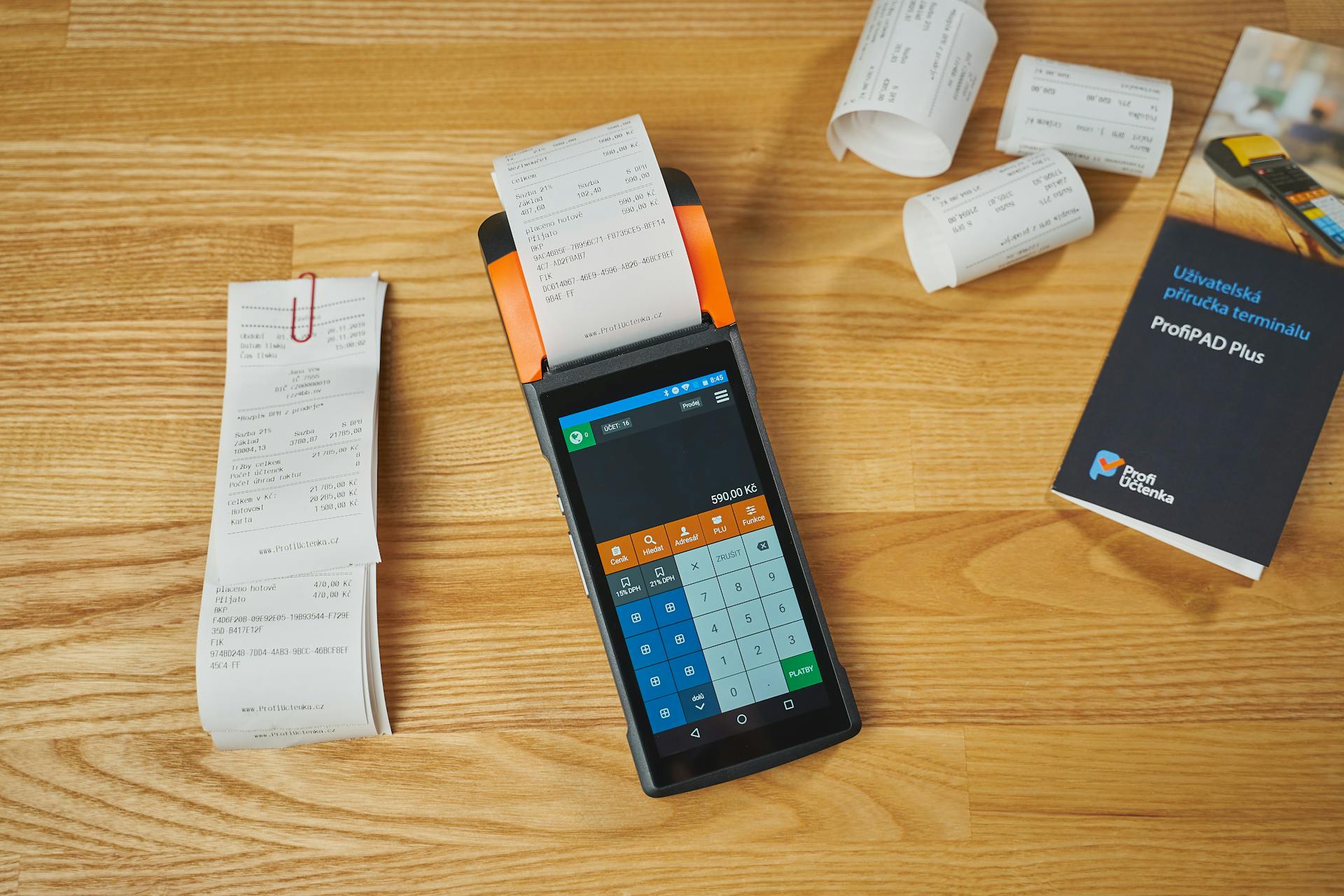 Electronic payment terminal with receipts, showcasing modern transaction processing on a wooden desk.