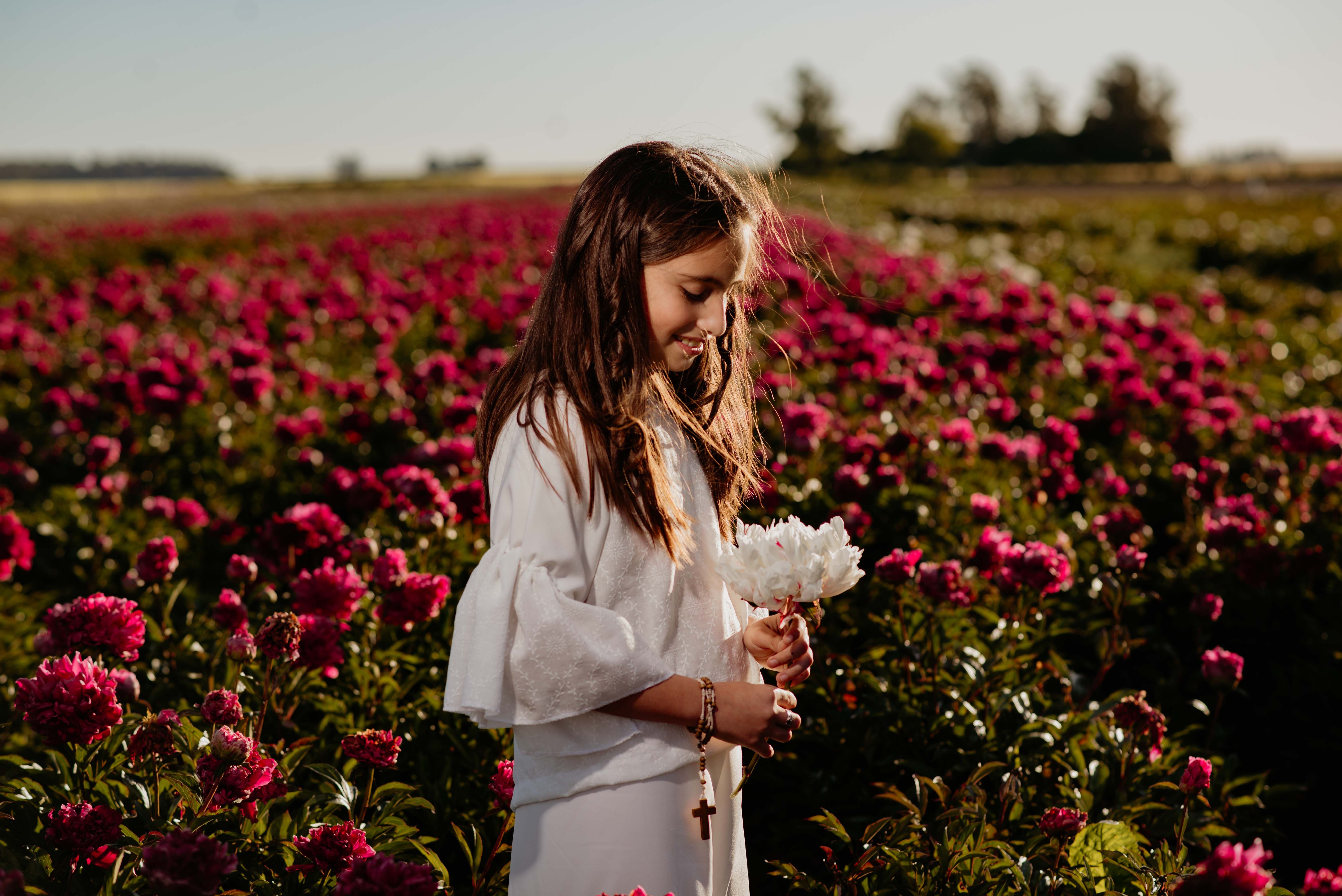 Young girl in white dress holding flowers in peony field · Free Stock Photo