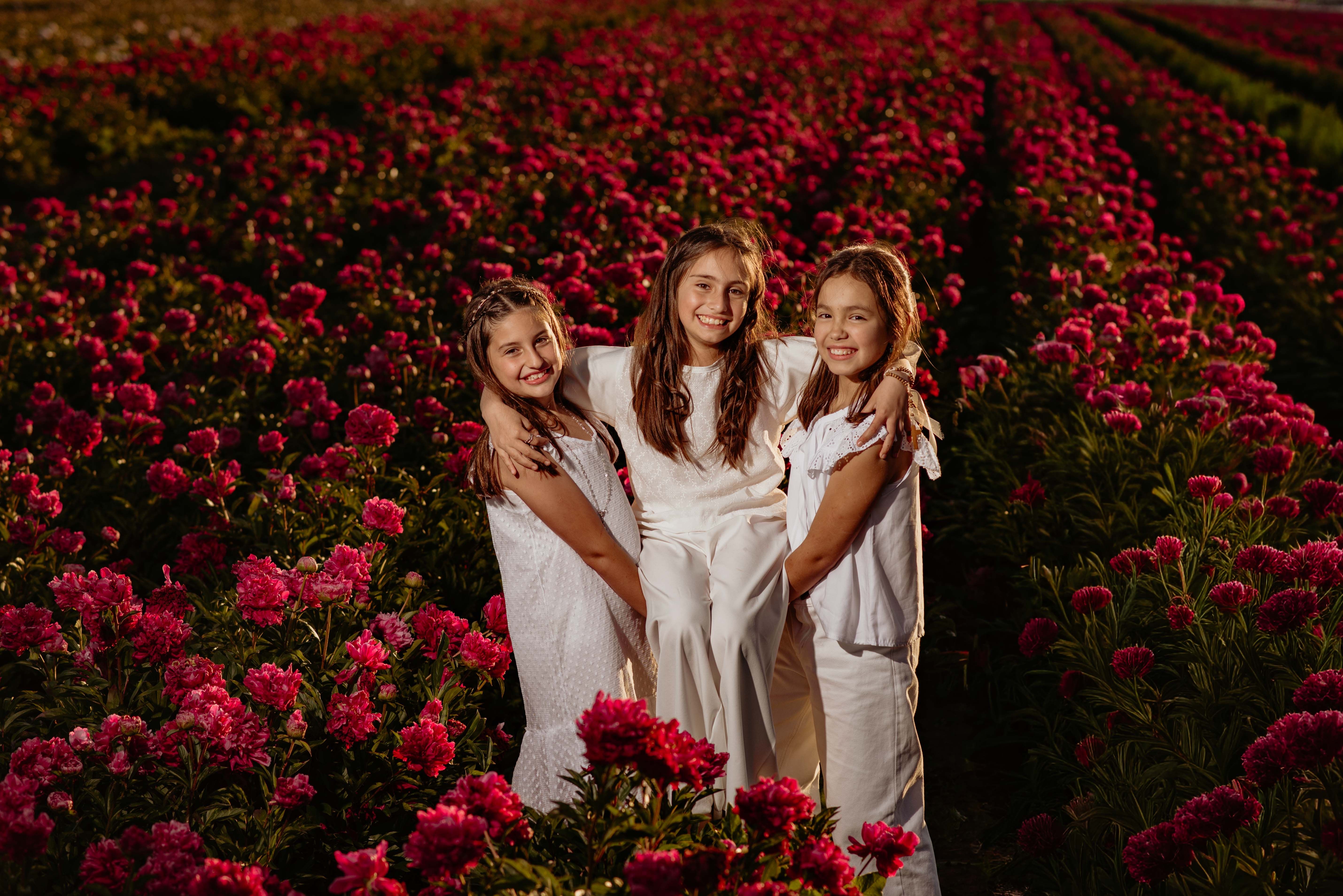 Three Girls Smiling in a Vibrant Flower Field · Free Stock Photo