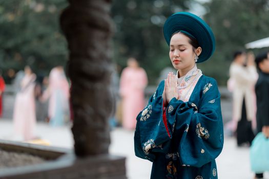 Woman in traditional attire with folded hands praying, showcasing cultural heritage.