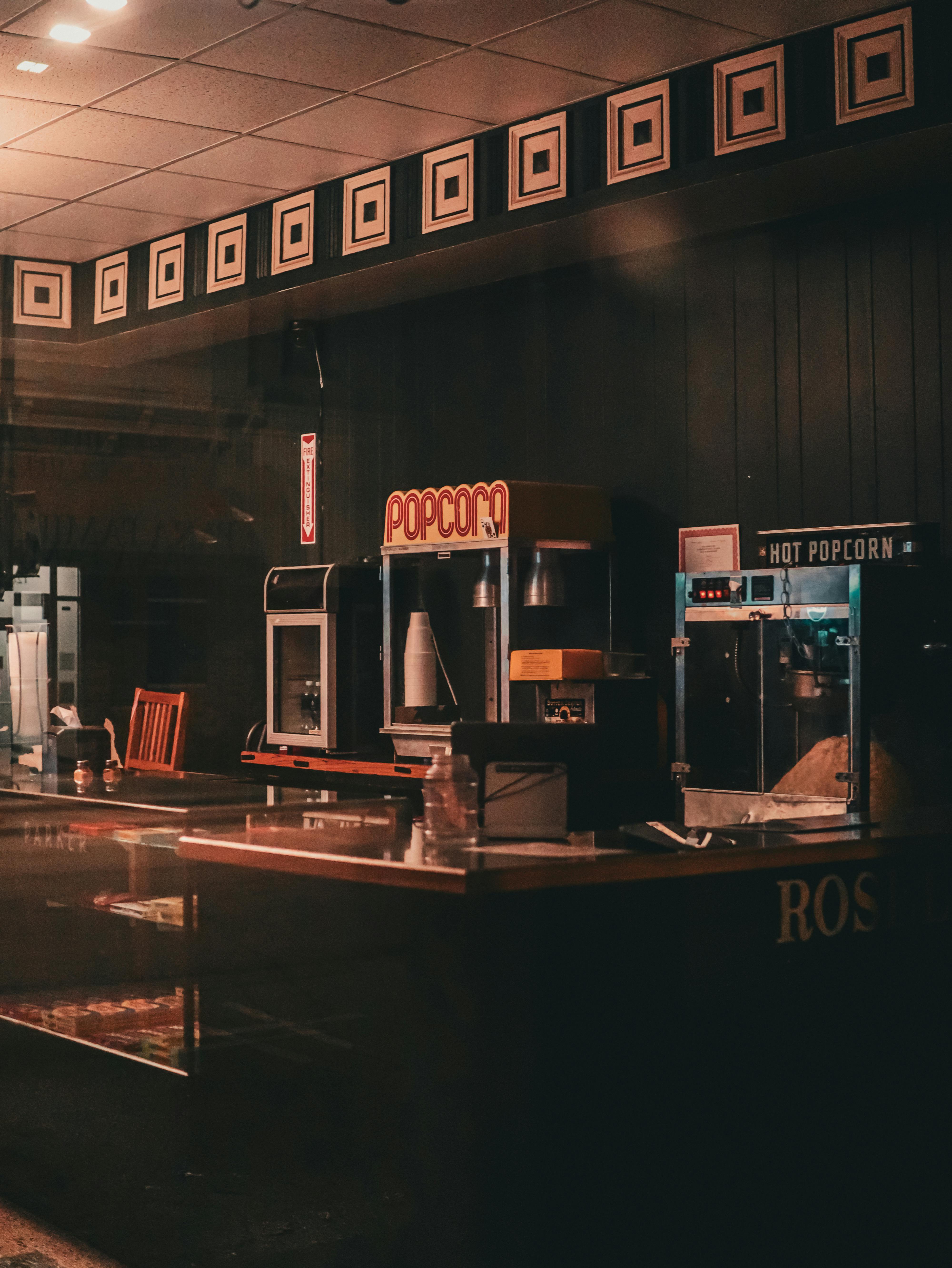 Gratuit Un stand de confiseries de cinéma rétro avec des machines à pop-corn, évoquant la nostalgie. Photos