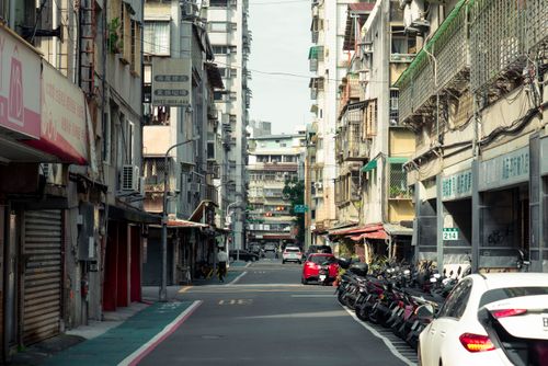 Free A street in Taipei City capturing the essence of urban life with buildings, parked scooters, and cars. Stock Photo