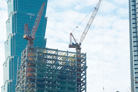 Cranes at construction site in Taipei with Taipei 101 in the background.