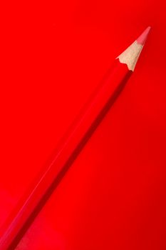 Close-up of a red colored pencil on a bright red background, vibrant colors.