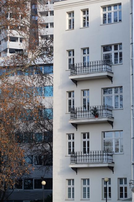 A contemporary urban apartment building with classic-style balconies and white facade.