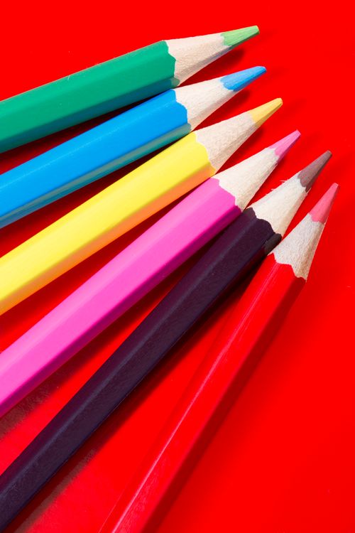 Free Vibrant colored pencils arranged on a striking red backdrop. Stock Photo