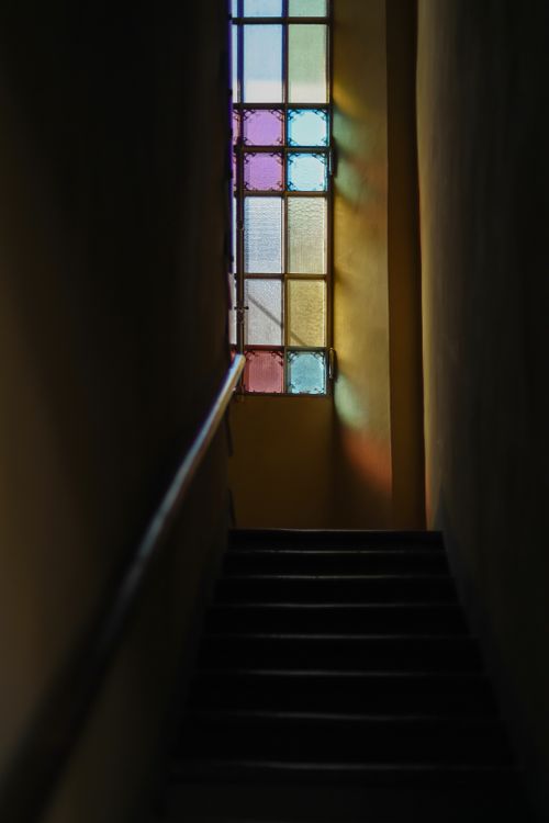 Free Atmospheric staircase with colorful stained glass window casting light. Stock Photo