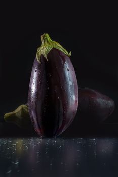 Close-up of fresh eggplant with water droplets against a dark background.
