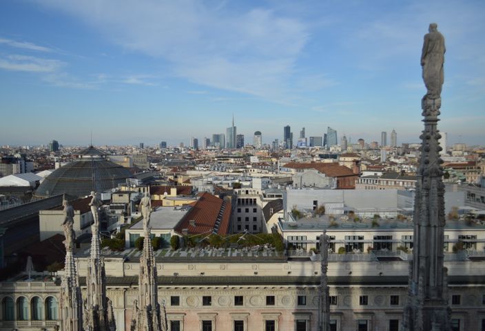 Captivating aerial view of Milan's skyline from atop the Duomo with a clear blue sky backdrop.