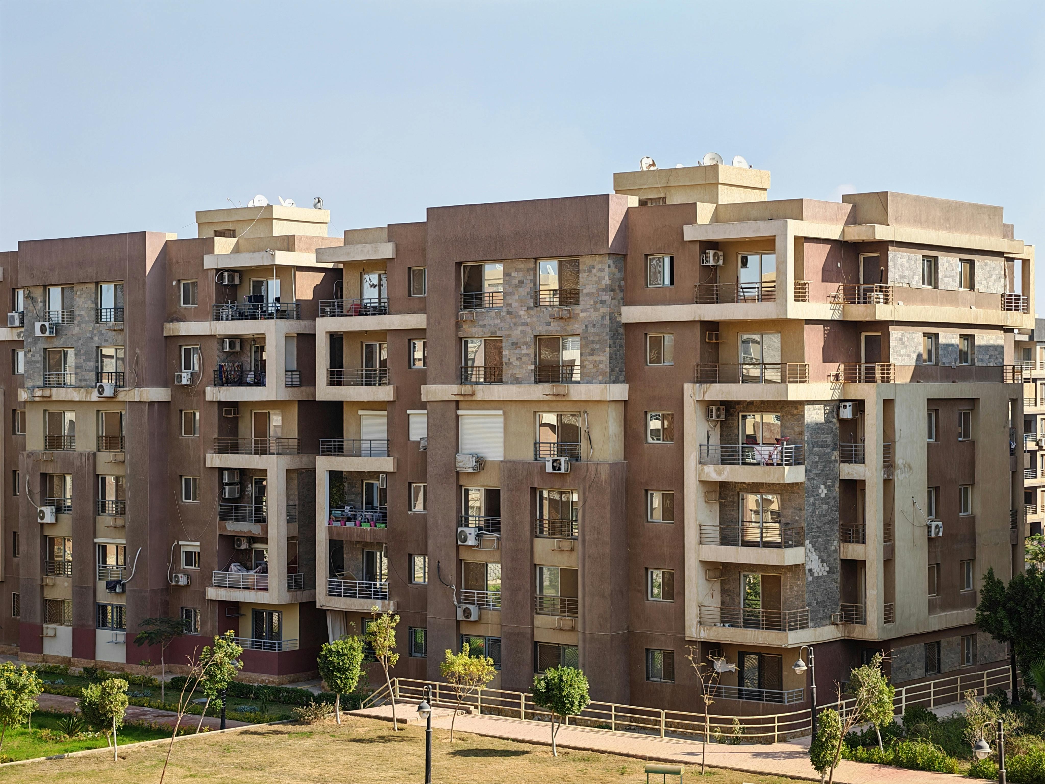 Contemporary multi-story apartment building with balconies in a sunny urban setting.