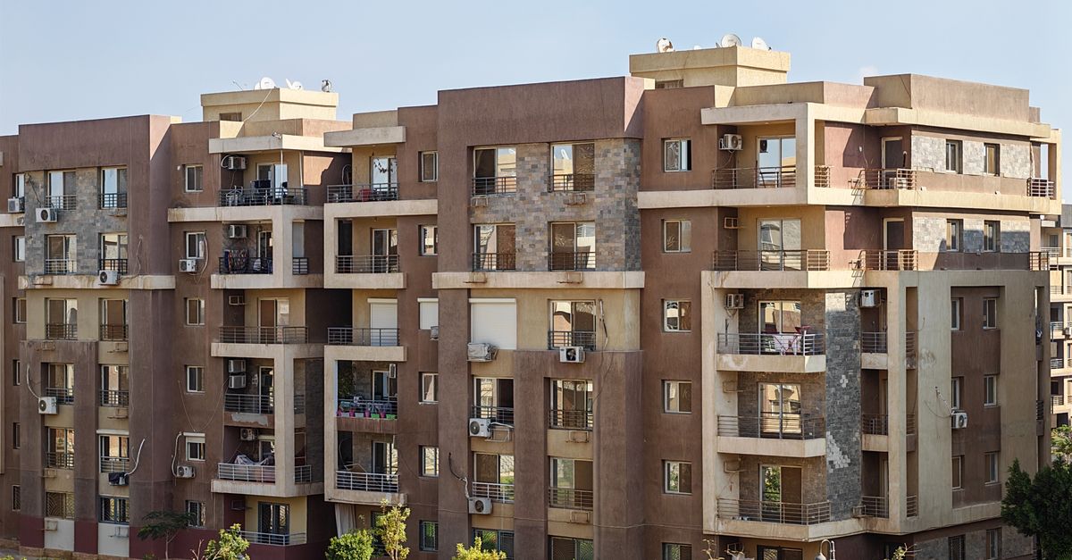 Contemporary multi-story apartment building with balconies in a sunny urban setting.