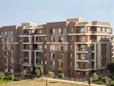 Contemporary multi-story apartment building with balconies in a sunny urban setting.