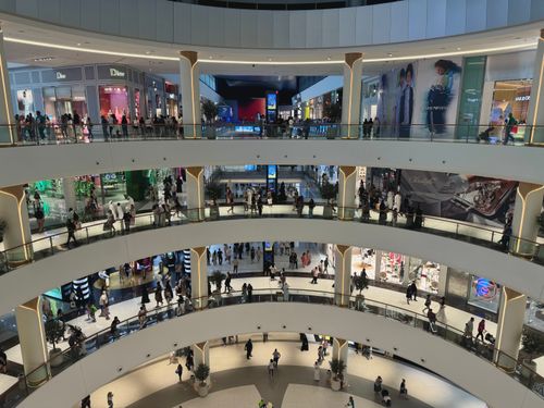 Free Wide-angle view of shoppers in the luxurious multi-level interior of Dubai Mall, the heart of modern retail. Stock Photo