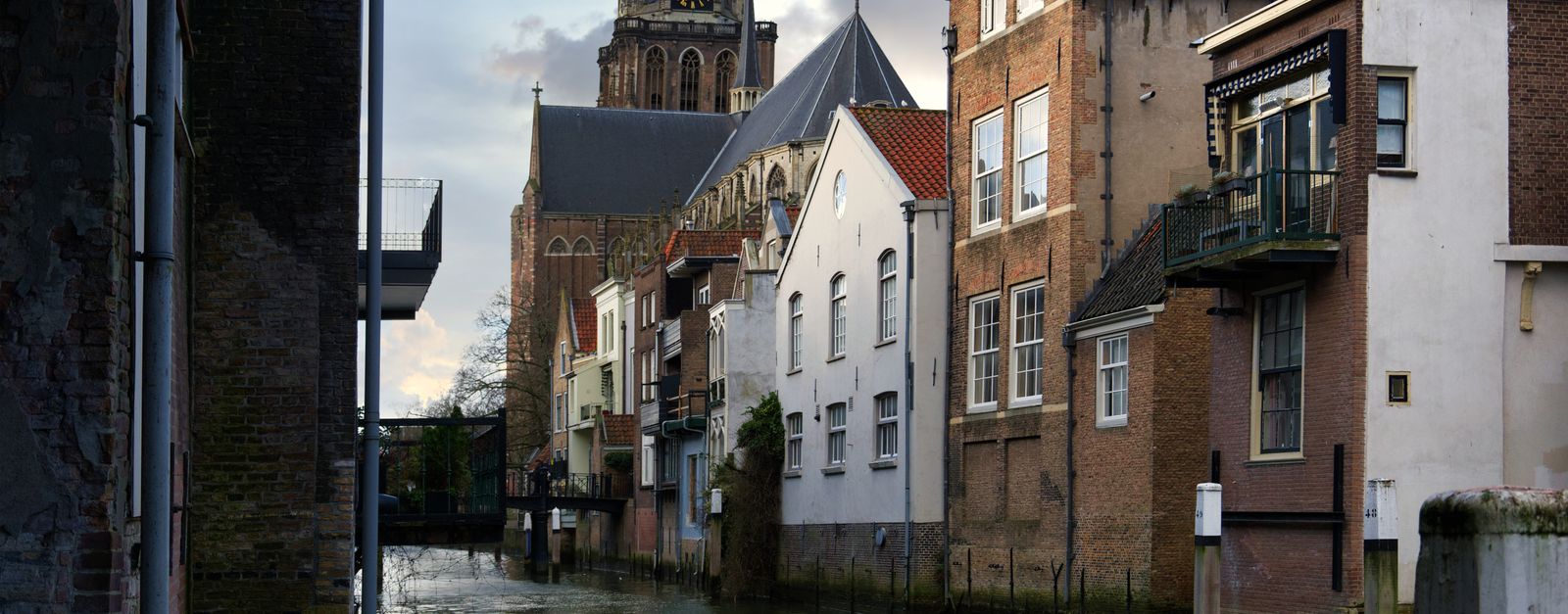 Scenic view of Dordrecht canal with historic church and residential buildings.