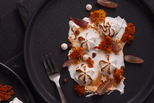 Free Artistic dessert featuring honeycomb and cream on a dark plate. Stock Photo